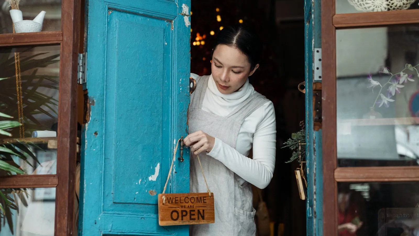 A shop owner turning the sign on her front door to Open