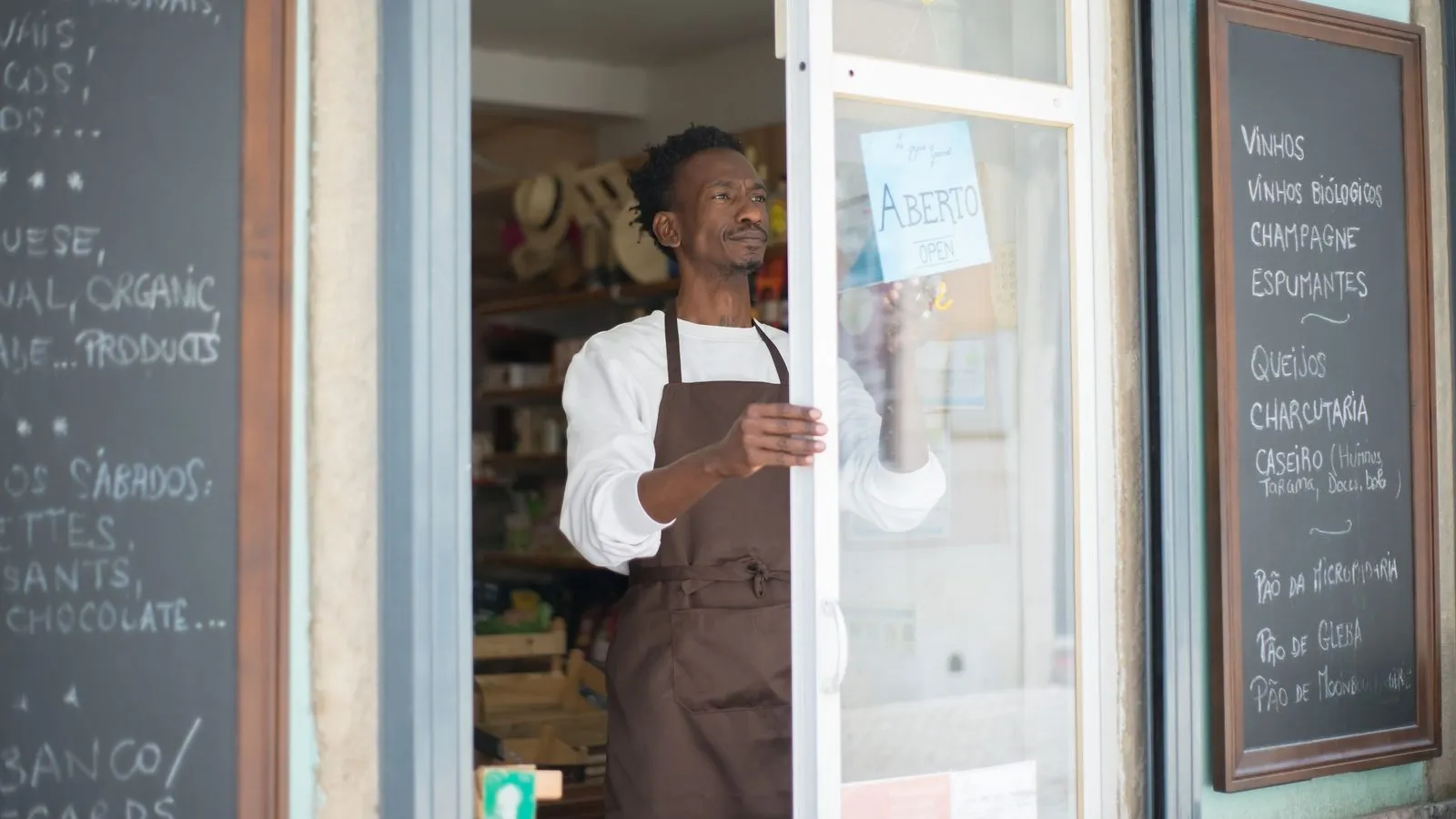 A shopkeeper hanging the Open sign in his shop door